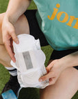 A person holding an organic bamboo incontinence pad, showcasing its ultra-thin and absorbent design.