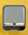 joni Model A open period care dispenser on a yellow brick wall