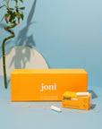 Yellow casepack of joni regular tampons for commercial washrooms with a blue background and bamboo