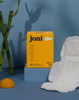 Bamboo period pads by joni in a vibrant setting with bamboo leaves and a citrus element, showcasing sustainable hygiene.