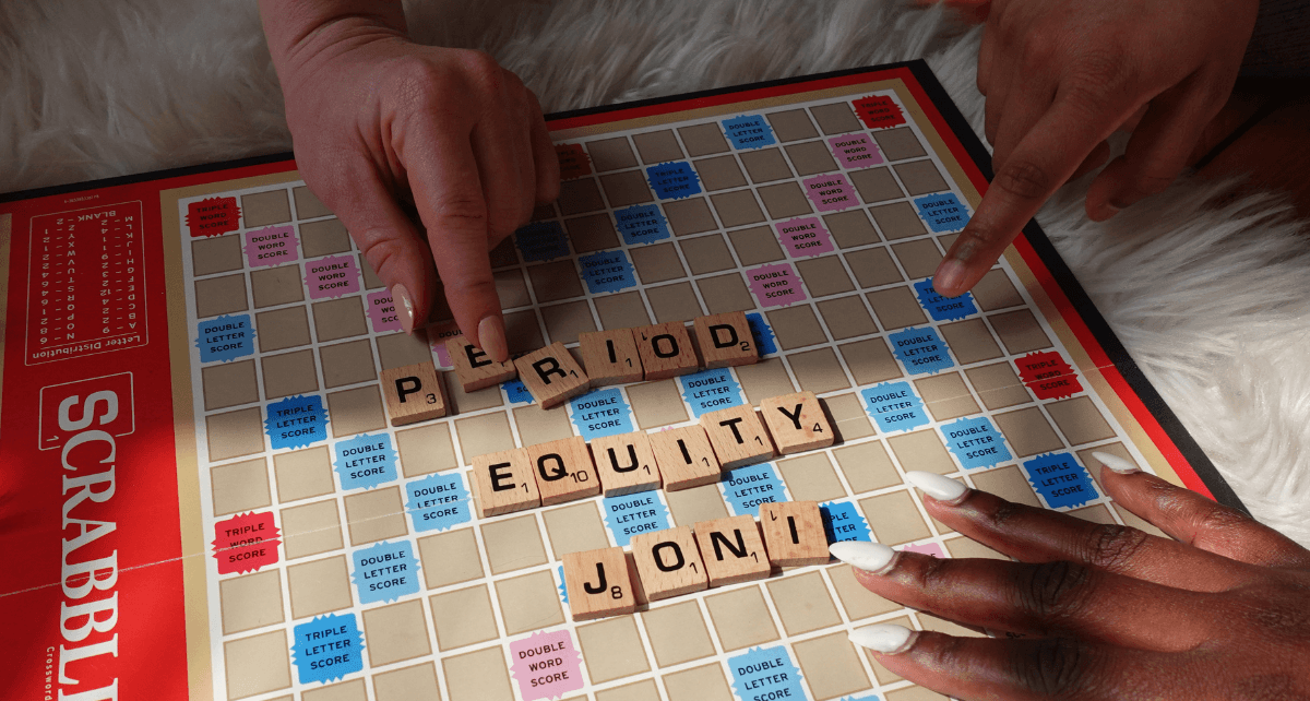 Hands playing Scrabble with tiles spelling out 'period' and 'equity', emphasizing the topic of period myths.