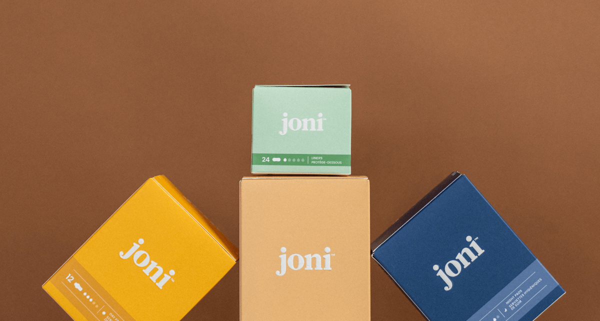 joni period pads in boxes stacked up on brown background