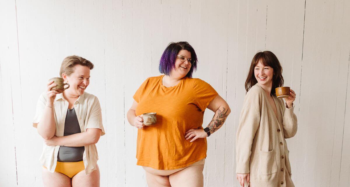 Three diverse menstruators stand in t-shirts and underwear