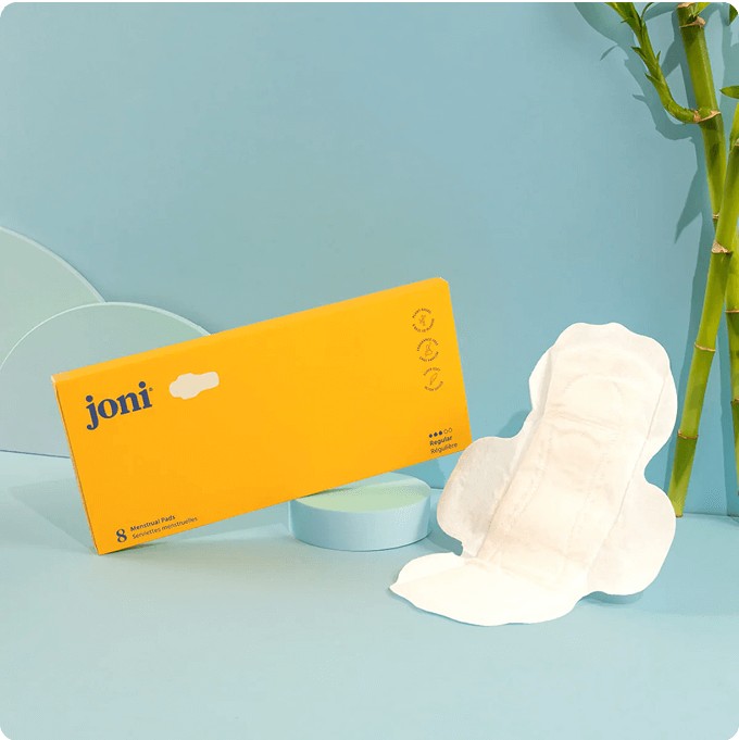 A pack of joni regular pads in a yellow box and one unwrapped pad to show the sweet spot in sustainable period care