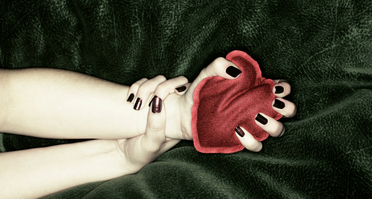 Hands squeeze a red plush heart