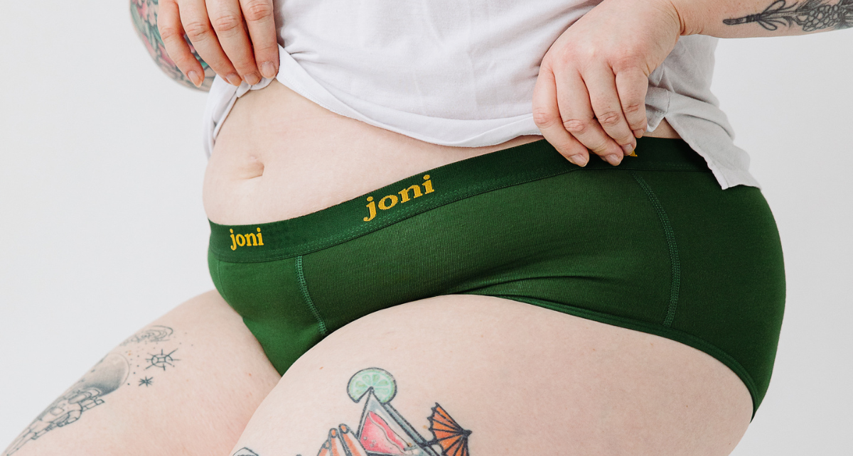 A closeup of joni period underwear on the torso of a tatooed person