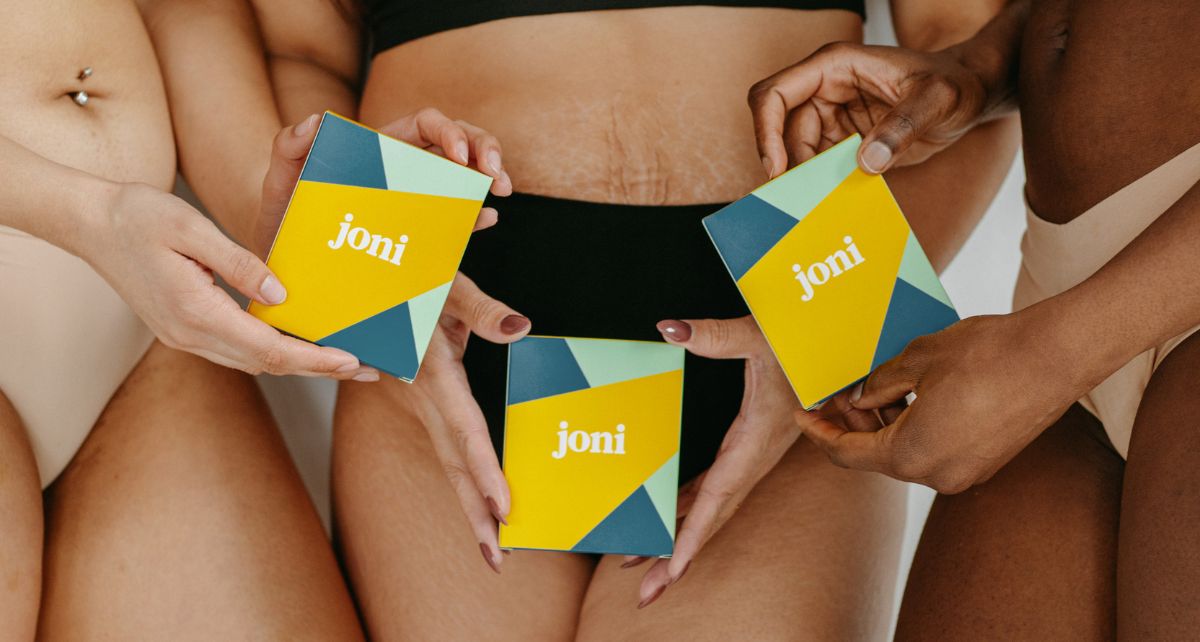 Three individuals holding joni branded boxes of natural, plant-based period care products, promoting feminine hygiene.