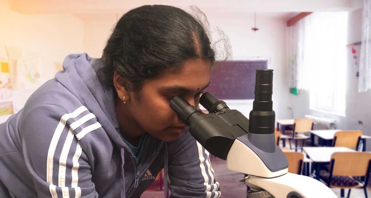 Young student scientist in a class lab looking in a microscope