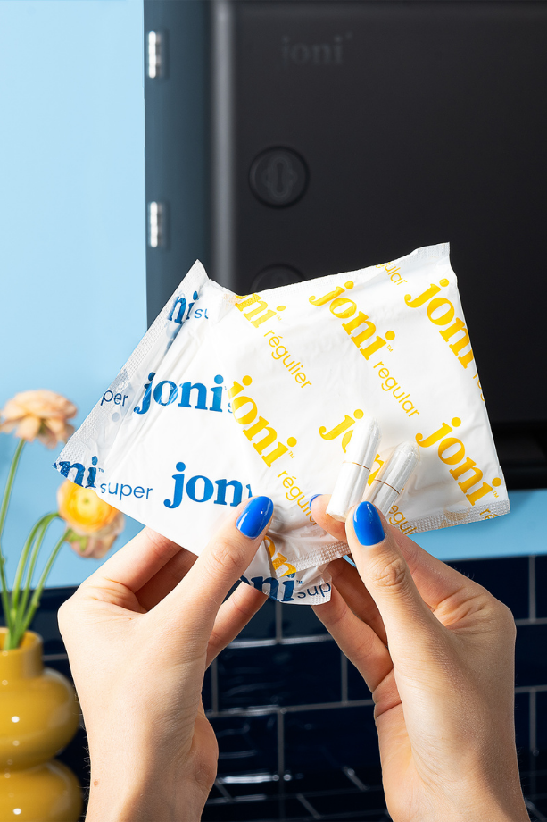 Hands holding multiple 'joni' brand packets with a blurred background